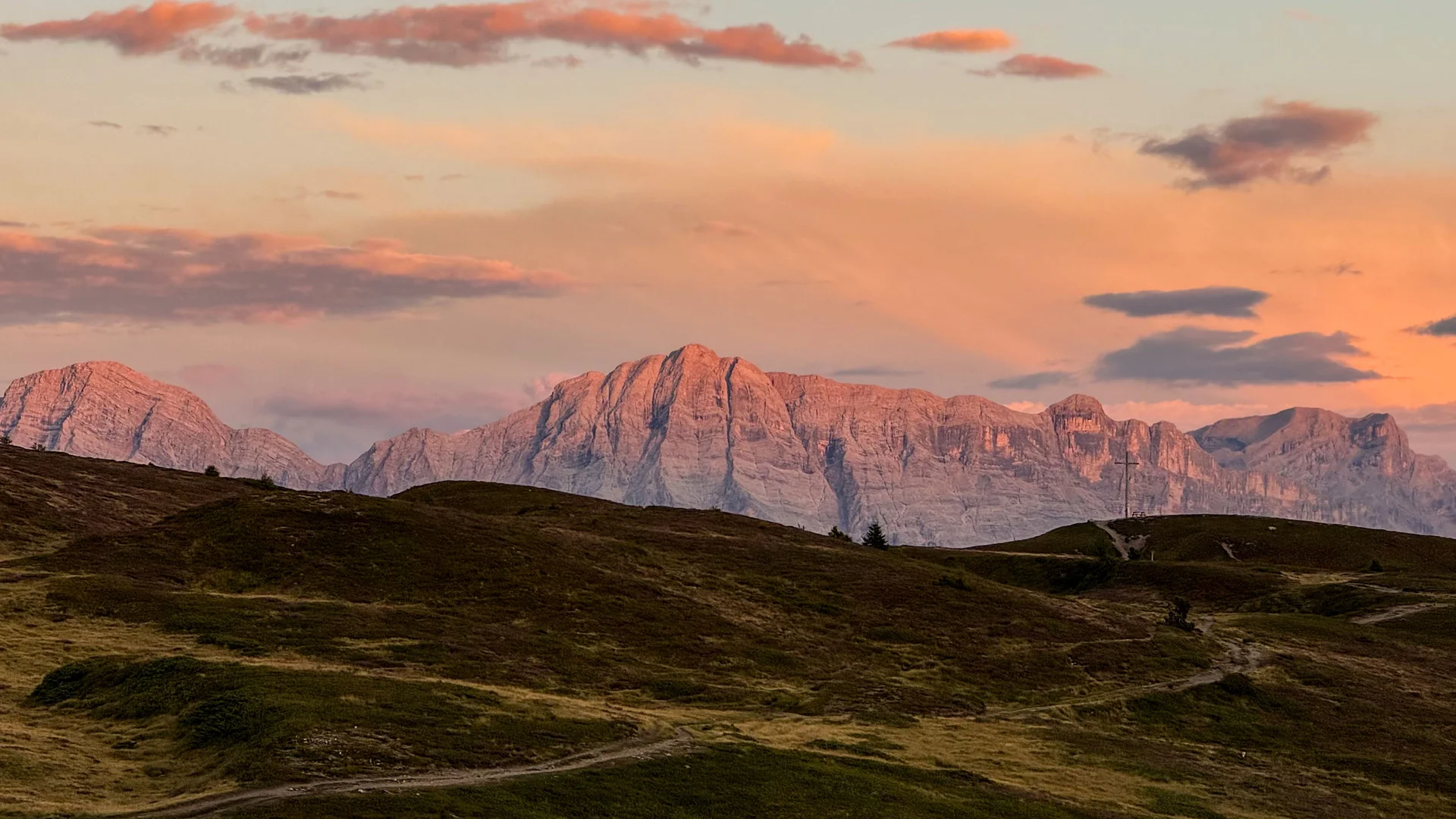 Ihr Chalet in den Dolomiten mit privater Sauna Alpengipfel leuchten im Abendlicht über dunklen, sanft hügeligen Wiesen